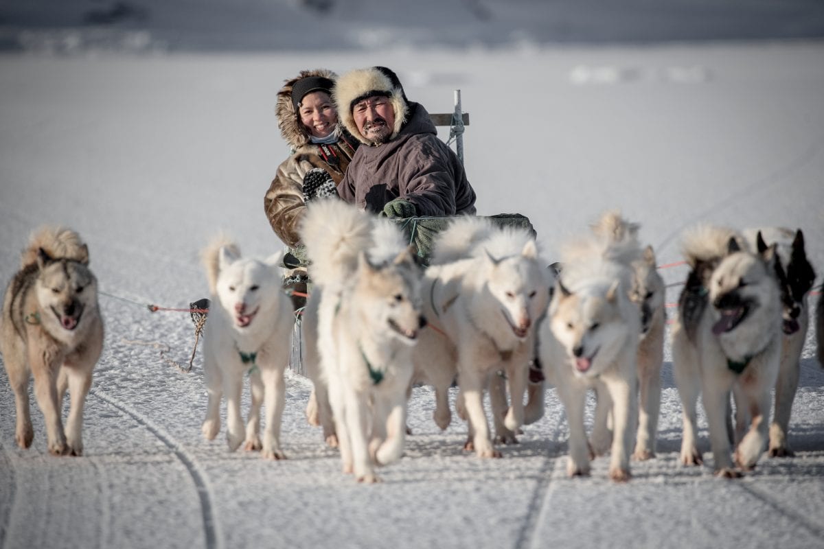 https://www.greenland-travel.com/wp-content/uploads/2019/04/a-chinese-traveler-with-her-guide-and-dog-musher-on-a-sled-near-ilulissat-in-greenland-_1_-1200x800.jpg
